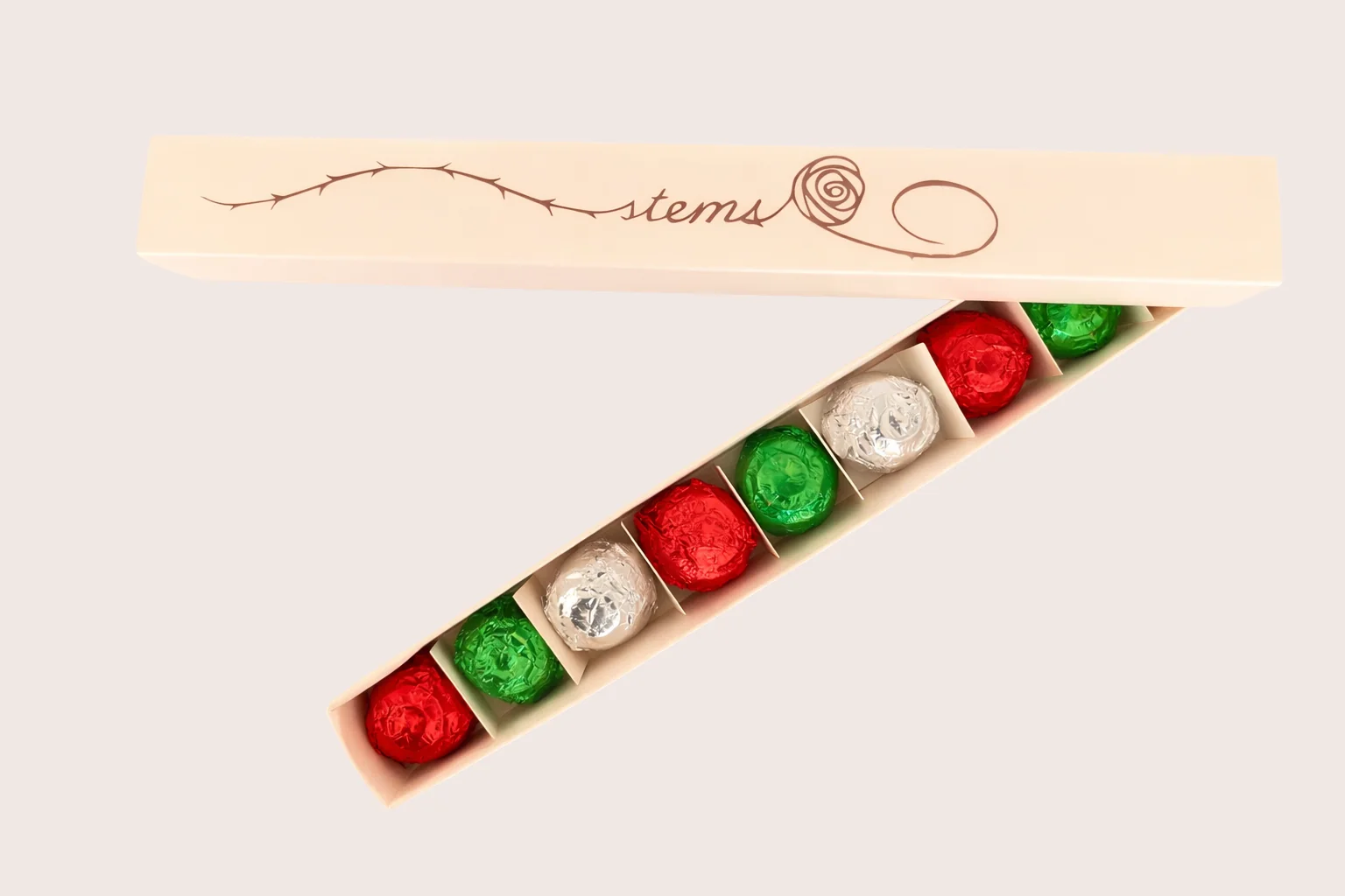 Caja abierta de 9stems mostrando los 9 bombones envueltos en papel rojo, verde y plateado